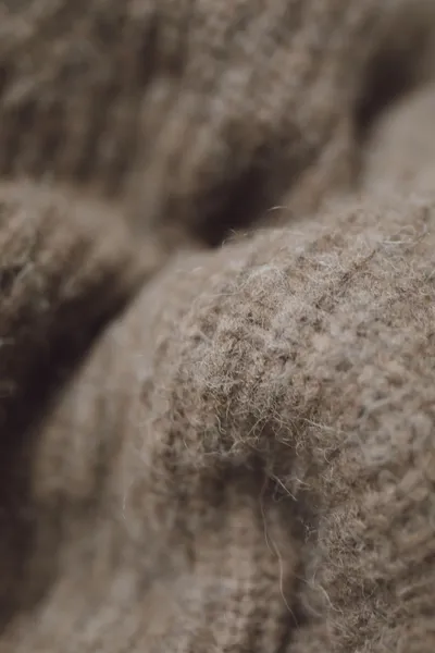 Gros plan sur un tricot de laine brune dont les fibres se soulèvent en duvet à la surface