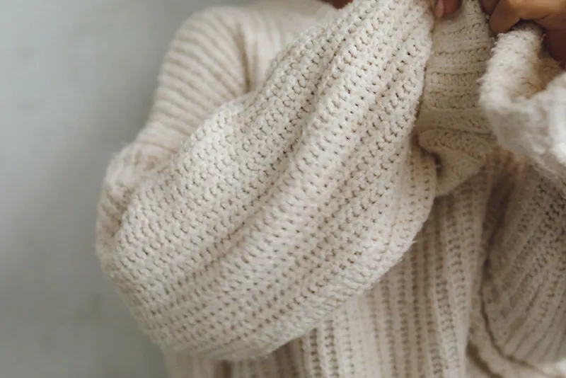 Gros pull en maille côtelée écrue aux manches bouffantes, vu de près