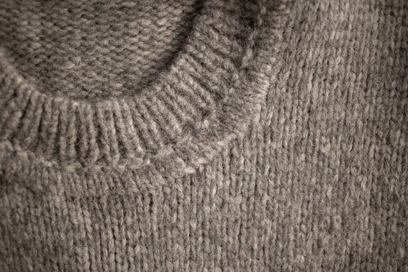 Encolure ronde en côtes d’un pull de laine grise, maille jersey régulière vue de près